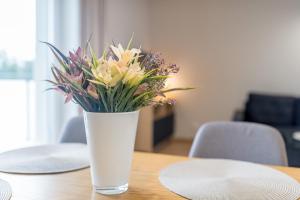 Alvista Apartamenty في ميكلينكي: مزهرية من الزهور تقف على طاولة