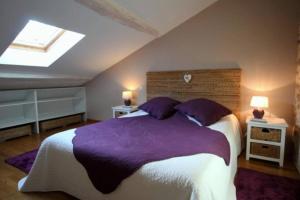 um quarto com uma cama grande com lençóis e almofadas roxos em Le Moulin du Château em Dompierre-les-Églises