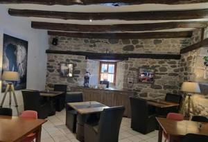 a restaurant with tables and chairs and a stone wall at Le clos de Banes in Banes