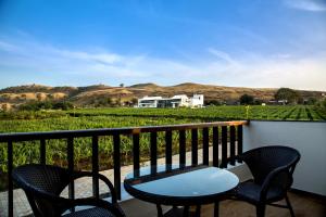 a table and chairs on a balcony with a view of a field at Soma Vineyard Resort -Nashik in Nashik