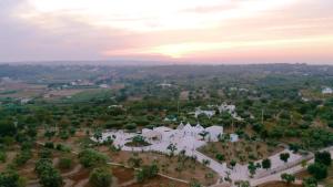 una vista aerea di una casa bianca con il tramonto sullo sfondo di Petranima Wellness in Trulli a Ostuni