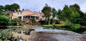 a large house sitting on the side of a river at Hotel Pont De Senard in Montaigu-Vendée