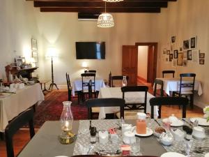 a dining room with tables and chairs and a tv at Monte Rosa Guesthouse in Rawsonville