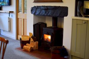 a wood stove in a living room with logs at Bottom Shop, Elterwater in Chapel Stile +10 photos