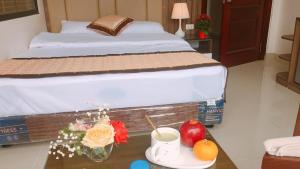 1 dormitorio con 1 cama y 1 mesa con flores y fruta en Khách sạn Phương Nam, en Pa Hiem (1)