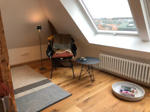 Zimmer im Dachgeschoss mit einem Stuhl und einem Fenster in der Unterkunft RaumAusbeute Design Apartment Hoher Priester in Detmold