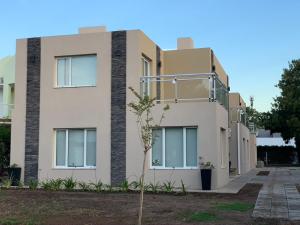una casa con un árbol delante en Complejo Los Cardenales, en Monte Hermoso