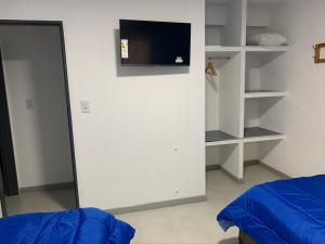 Un dormitorio con una cama y un televisor en una pared. en Complejo Los Cardenales, en Monte Hermoso