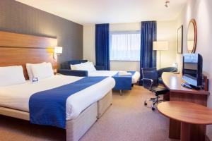 ブレインツリーにあるHoliday Inn Express Braintree, an IHG Hotelのベッド2台、デスク、テレビが備わるホテルルームです。