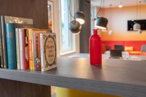 a shelf with books and a red bottle on it at Campanile Vienna South in Vienna