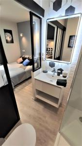 baño con lavabo, cama y espejo en Home&Work 101 - HYPERCENTRE - Parking à proximité, en Niort