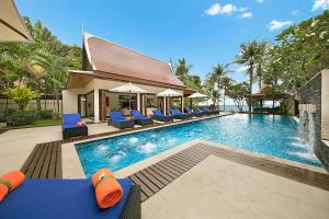 - une piscine avec des chaises longues bleues et l'océan dans l'établissement Dhevatara Cove, à Lipa Noi