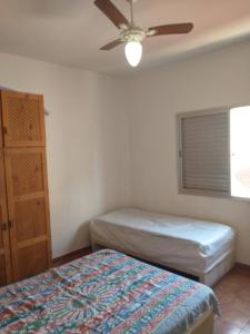a bedroom with two beds and a ceiling fan at O AP DO FÊ - Apartamento Praia Grande - Vila Tupi in Praia Grande +72 photos