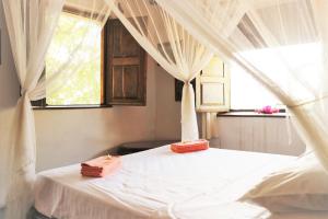 Miti Miwiri في Ibo: غرفة نوم بسرير ابيض مع ستائر ونافذة