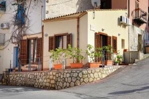 a house with potted plants on a stone wall at Casa Vacanze Gorgonia in Castellammare del Golfo