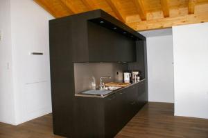 una cocina negra con fregadero en una habitación en Perle des Alpes, Bettmeralp, Switzerland en Bettmeralp