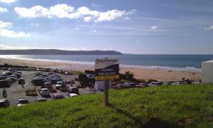 a parking lot next to a beach with cars parked at Southover Beach in Woolacombe