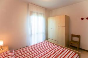 a bedroom with a bed and a refrigerator and a chair at Torcello in Bibione