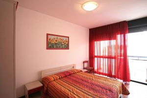 sypialnia z łóżkiem i oknem z czerwonymi zasłonami w obiekcie Panfilo w Caorle