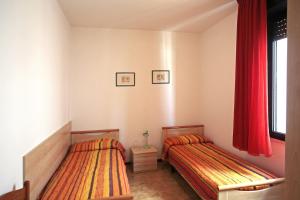 2 Betten in einem Schlafzimmer mit roten Vorhängen in der Unterkunft Panfilo in Caorle