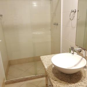 a bathroom with a sink and a glass shower at Hotel Meaípe in Guarapari