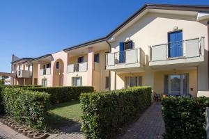 un edificio de apartamentos con arbustos delante de él en Quercia Lido Altanea, en Caorle