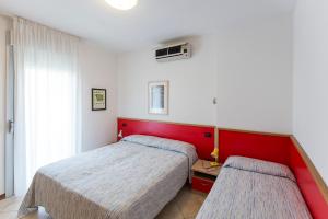 1 dormitorio con 2 camas y cabecero rojo en Robinia/Pinetine Lido Altanea, en Caorle