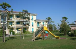 un parque infantil con un tobogán frente a un edificio en Lecci Lido Altanea, en Caorle