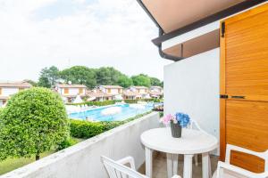 Un balcón con mesa y sillas y una piscina. en Sole B, en Bibione