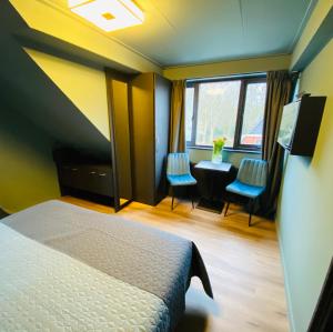 a bedroom with a bed and a desk and windows at Hotel Zee Bergen in Bergen