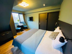 een slaapkamer met een bed, een bureau en een raam bij Hotel Zee Bergen in Bergen