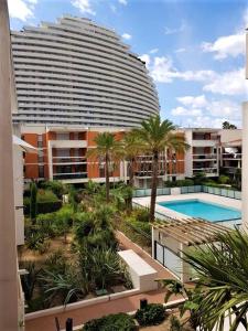 a large building with a swimming pool and palm trees at Appartement Villeneuve Loubet in Villeneuve-Loubet