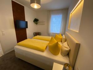 a bedroom with a bed with yellow sheets and pillows at Pension Alscher Garni in Goslar