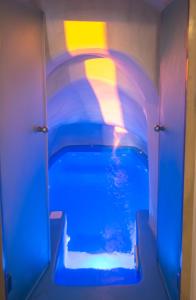 a swimming pool in a room with a blue light at Kastro Oia Houses in Oia