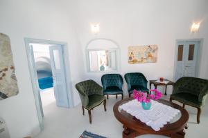 um quarto com cadeiras verdes e uma mesa com flores em Kastro Oia Houses em Oia