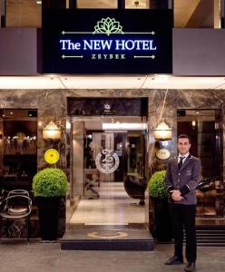 un homme en costume debout devant un hôtel dans l'établissement The New Hotel Zeybek, à Izmir
