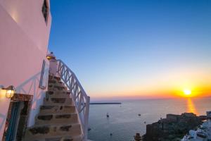 een trap die leidt naar een zonsondergang boven de oceaan bij Kastro Oia Houses in Oia