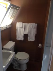 a bathroom with a toilet and a sink and towels at Amber Lantern Motel in Lake George