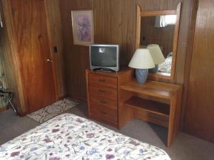Dormitorio con cama y tocador con TV en Amber Lantern Motel, en Lake George