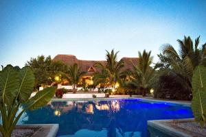 a swimming pool in front of a house with palm trees at Pemba Paradise in Makangale