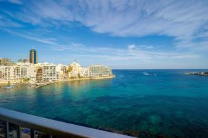 a view of the ocean from a balcony of a city at Spinola Bay top floor seafront 3 bedroom Apartment with panoramic sea views - by Getawaysmalta in St. Julianʼs