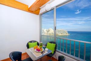 balcón con mesa, sillas y vistas al océano en Spinola Bay top floor seafront 3 bedroom Apartment with panoramic sea views - by Getawaysmalta, en San Julián