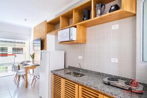 a kitchen with a white refrigerator and a table at Estúdios 3 Praias in Ubatuba