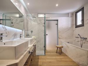 een badkamer met 2 wastafels, een bad en een douche bij The Royal Blue a Luxury Beach Resort in Panormos Rethymno