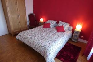 a bedroom with a large bed with red walls at Les ammonites gîte de charme en Bourgogne in Guillon