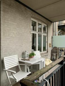 two white chairs and a table on a balcony at ApartmentInCopenhagen Apartment 547 in Copenhagen +10 photos