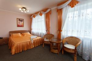 a bedroom with a bed and two chairs and a window at Olginskaya Hotel in Pskov