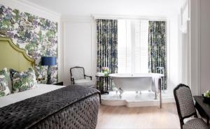 una camera con letto e una vasca da bagno in una finestra di The Kensington Hotel a Londra