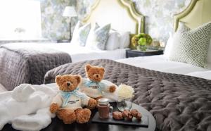 a teddy bear sitting on top of a bed at The Kensington Hotel in London