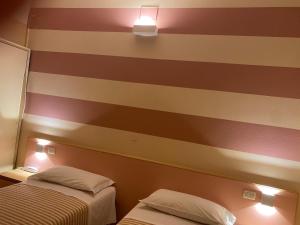 two beds in a room with a striped wall at Hotel Savio in Cesena